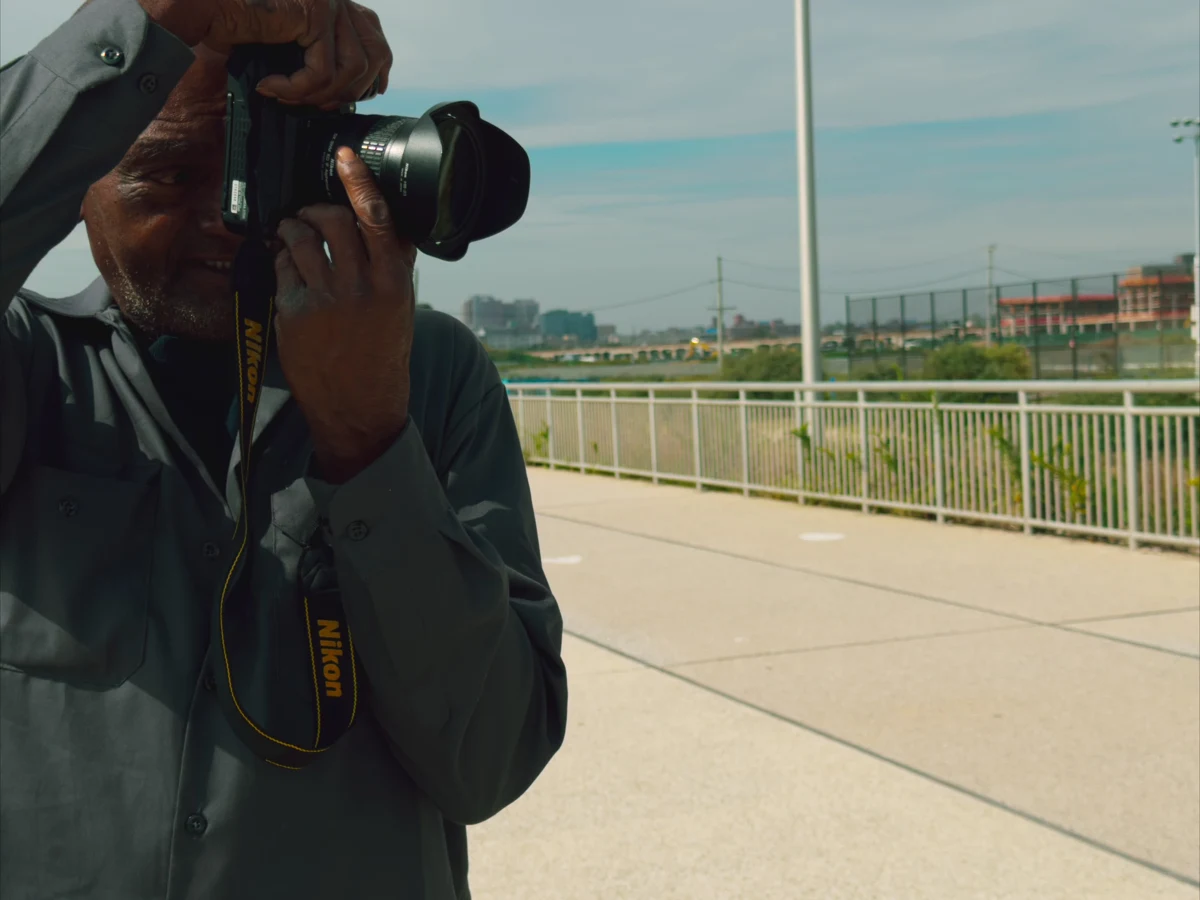 Kenny Harris smiling with his camera raised to his eye